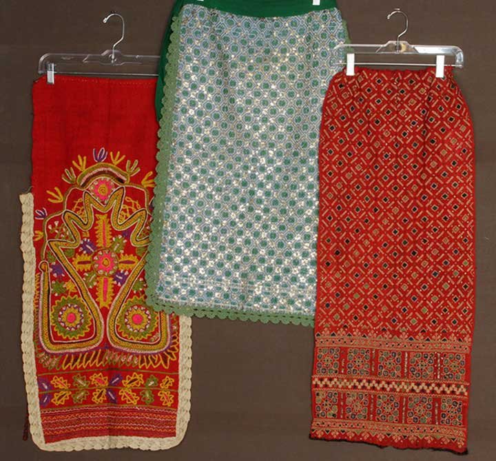 THREE APRONS, ROMANIA & ALBANIA, c. 1900: 1 Albanian red wool embroidered w/ large motifs in bright colors; 2 Romanian w/ allover geometric patterns: 1 double sided white cotton w/ blue embroidery, silver sequins & green beads; 1 red wool w/