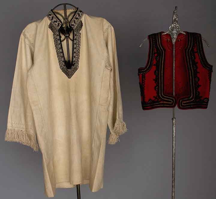 TWO MEN'S REGIONAL GARMENTS, c. 1900: 1 Yugoslavian cream cotton long shirt w/ black embroidery on collar & front placket opening, beige embroidery on fringed sleeves, Ch 38", L 34"; 1 Albanian red boiled wool vest trimmed in black wool &