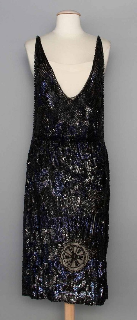 BLUE & BLACK SEQUINED PARTY DRESS, 1920s: All-over blue & black sequined pattern in abstract shapes, jet beads on net rondels on F&B, low cut F&B neckline, L 44", (waist seam taken in, some missing sequins, missing underdress) very good.