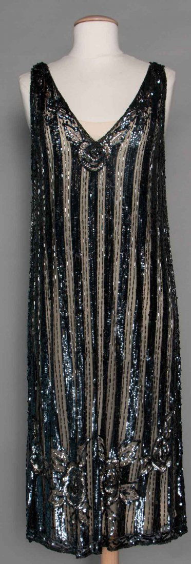 SEQUINED FLAPPER DRESS, 1920s: Black tulle, 1" vertical bands of pewter sequins w/ 2 rows of bugle beads between, beads & sequins in floral pattern near hem, sleeveless, V neck, B 34"-36", H 36"-40", L 44", (few trim losses) very g