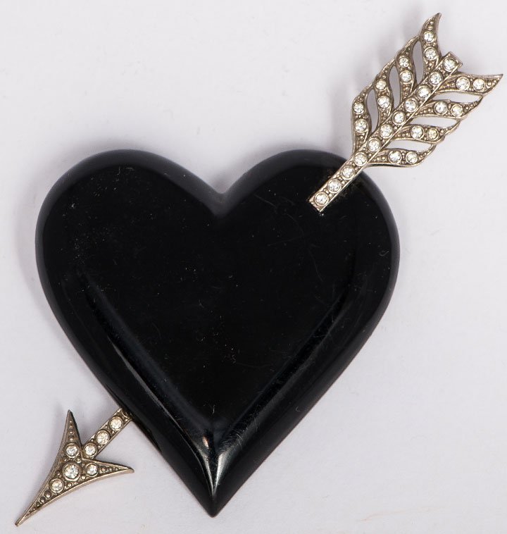 YVES SAINT LAURENT BROOCH, LATE 20TH C: Black plastic heart pierced by silver metal & rhinestone arrow, marked "YSL" on pin back, Ht 2.75", excellent. Suddon-Cleaver Costume Collection