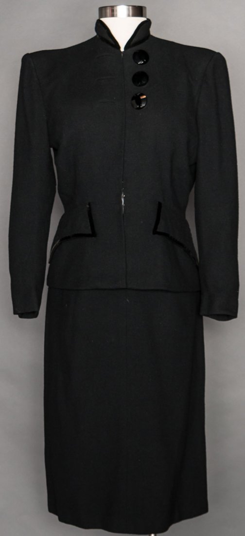 GILBERT ADRIAN SKIRT SUIT, LATE 1940s: "Adrian Original" black wool, padded shoulder jacket, band collar, 3 large jet buttons w/ faux button holes, large pocket flaps, pencil skirt, B 38"-42", W 31", Skirt L 27", excellent.