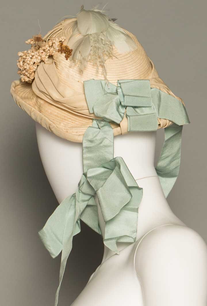 WHITE STRAW WEDDING BONNET, 1870: Painted straw, domed oval crown, small up turned brim, blue ribbon, small cloth flower & feather trim, (floral/feather trims weary) very good.