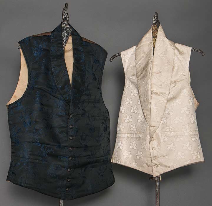 TWO MEN'S SILK VESTS, 1840-1860: Both w/ shawl collars & linen backs: 1 ivory figured brocade w/ small blossoms, Ch 36", L 18" (brown stain on linen back); 1 black w/ small sapphire blue patterned vines & flowers, dark brown backing 