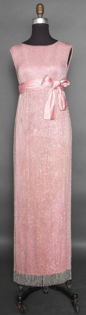 NORELL JEWELED EVENING GOWN, c. 1966: Dusty rose silk crepe covered in narrow rows of rhinestones, jewel neckline, sleeveless, empire waist w/ satin tie sash, silk lining, 3" beaded hem fringe, label "Norman Norell", B 32", W 27.5", L 52"