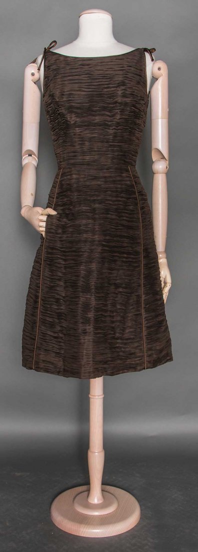 SYBIL CONNOLLY COCKTAIL DRESS, DUBLIN, 1960s: Dark brown, surface hand pleated horizontally, sleeveless, ballet neckline w/ shoulder ties, bell skirt w/ CF piped panel, 2 inset side pockets, labeled, B 36", W 27", L 40", excellent. Museum De-Acce