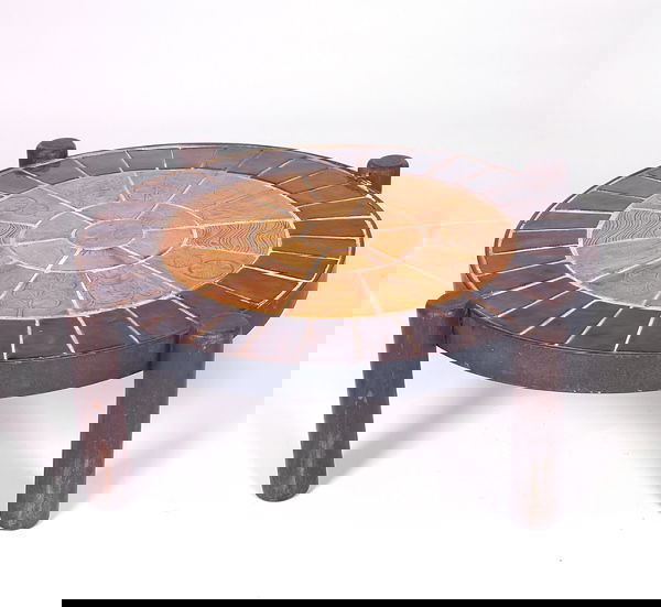 ROGER CAPRON (Attr.) Circular tile-top coffee tabl: ROGER CAPRON (Attr.) Circular tile-top coffee table with a variety of embossed designs covered in amber glossy glaze with dark brown border, on cylindrical wood legs. Some grout loss to top. Unmarked.