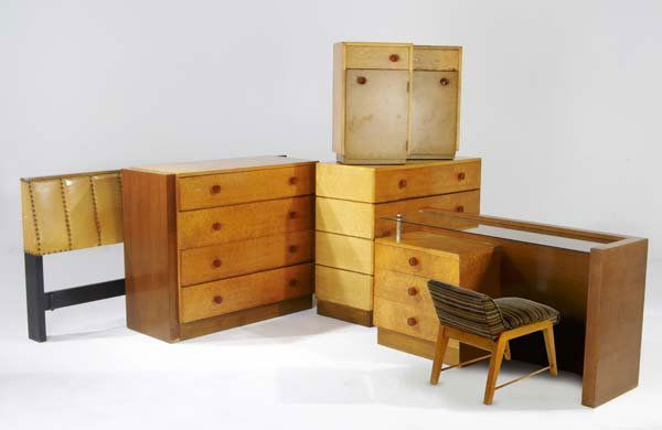 GILBERT ROHDE / HERMAN MILLER Seven-piece bedroom: GILBERT ROHDE / HERMAN MILLER Seven-piece bedroom suite consisting of a vanity and stool, two four-drawer chests with bakelite handles (one replaced), and a king-sized headboard. Marked with metal tag
