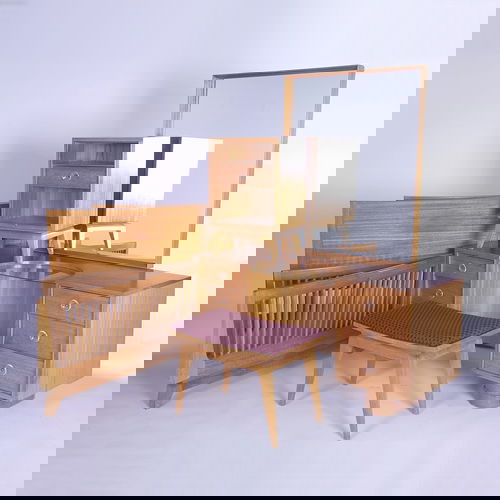 GILBERT ROHDE (Attr.) Eight-piece bedroom furnitu: GILBERT ROHDE (Attr.) Eight-piece bedroom furniture suite consisting of a six-drawer vanity and single-drawer nightstand with lucite pulls, an upholstered vanity stool, a wall-hanging mirror, and two