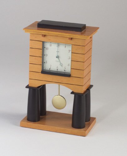 Fine MICHAEL GRAVES for ALESSI architect: Fine MICHAEL GRAVES for ALESSI architectural mantle clock of blonde and ebonized woods, with powder blue hands and gold-finished pendulum. Face marked Alessi/Graves. 9 3/4" x 6 1/4" x 3 1/2"