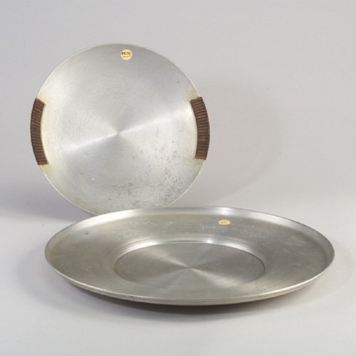 Two RUSSEL WRIGHT spun aluminum pieces: Two RUSSEL WRIGHT spun aluminum pieces: a shallow bowl with reed handles, and a large cheese tray. Some minor pitting to bowl, wear and scratches to tray. First one stamped "Russel Wright". Dia.: 12"