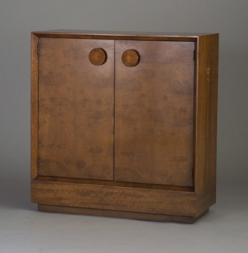 GILBERT ROHDE for HERMAN MILLER Paldao t: GILBERT ROHDE for HERMAN MILLER Paldao two-door cabinet with large circular wood pulls, five interior drawers and two adjustable shelves in black lacquer finish. Some veneer and touched-up chips. Herm