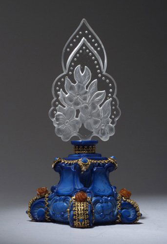 INGRID perfume bottle, circa 1920s, in op: INGRID perfume bottle, circa 1920s, in opaque blue crystal with clear stopper, in metalwork with bakelite rose jewels. Ht. 8 3/8 in (21 cm)