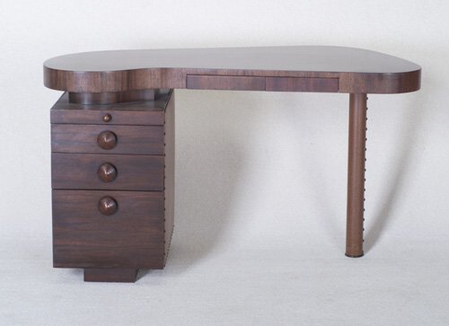 GILBERT ROHDE HERMAN MILLER single-pedes: GILBERT ROHDE HERMAN MILLER single-pedestal Paldao desk with raised, glass-covered kidney-shaped top and two shallow blind drawers, over pull-out shelf and three drawers with carved wood pulls, and ta