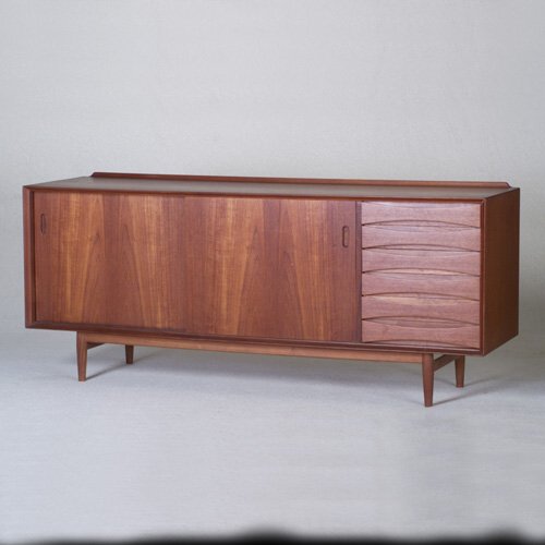 ARNE VODDER: Fine SIBAST FURNITURE teak sideboard with low backsplash, two sliding doors with recessed oval pulls concealing three shelves, flanking six drawers with hourglass fronts, on dowel-leg base with stretc