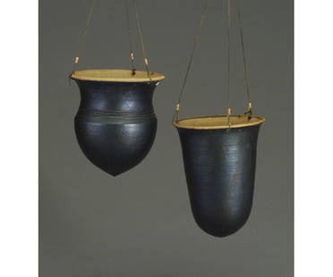 Two WILLIAM WYMAN stoneware hanging bask: Two WILLIAM WYMAN stoneware hanging baskets, one helmet-shaped and the other bullet-shaped, both covered in gunmetal glaze with original hanging wires. Small chips to rim of first one. Stamped WW. 10