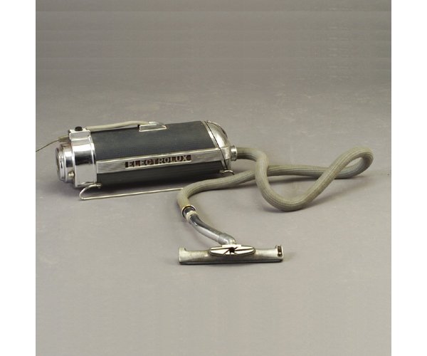 ELECTROLUX canister vacuum designed by L: ELECTROLUX canister vacuum designed by LURELLE GUILD with chrome and aluminum housing on "sled" base, with original power cord, hose, and single attachment. Marked. Canister: 9" x 22 1/2" x 7 1/2"