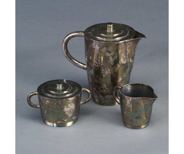 Three-piece LURELLE GUILD silver-plated: Three-piece LURELLE GUILD silver-plated Art Deco coffee service by WP with pot, covered sugar bowl and creamer, with ribbed bases and finials. Handle of coffee pot re-soldered, a few small dents. Stam