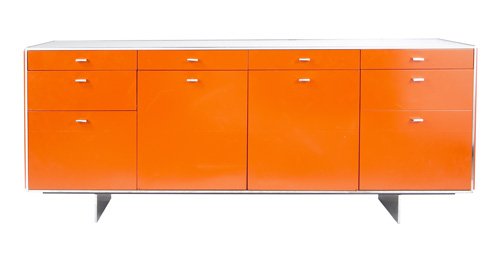 DAVIS ALLEN Credenza in polished chrome and orange: DAVIS ALLEN Credenza in polished chrome and orange enameled metal, with white laminate top and single interior shelf. Davis Allen foil label. 26 1/4" x 64 3/4" x 21 1/2"