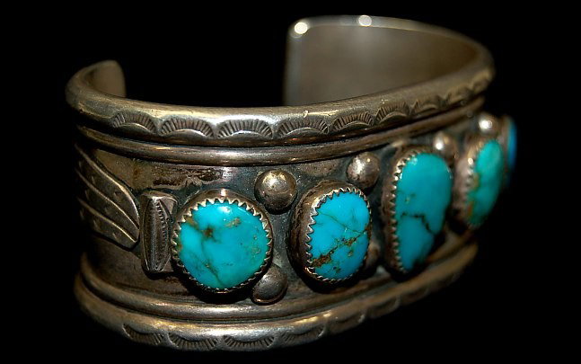 Navajo sterling old pawn 5 stone turquoise cuff: Navajo sterling old pawn 5 stone turquoise cuff having heavily stamped borders and applied sterling feathers to both sides, one stable natural hairline to one stone, c.1940-1950