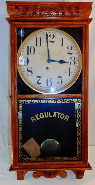 Regulator Wall Clock: Western Union Press Carved Oak Regulator Clock is in good condition. This clock has a Greek Keynote Stenciled Window Cabinet and retains it's original base and top. It measures 36"Tx17"A..