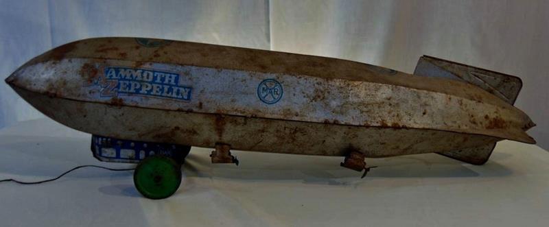 Mamoutle Zeppelin Pulltoy: A Mamoutle Zeppelin by Marx Toy Manufacturer Pulltoy. This 1920's Tin Lithographed Zeppelin Pulltoy retains it's original paint and stenciling and is in "played with" condition. It measures 28"L