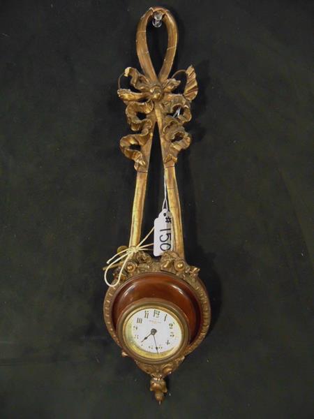 Ribbon Clock: French Wood and Gilt Plaster Garland Key Wind Ribbon Clock. Loss noted to garland. This clock measures 16"Tx4.5"Wx2"D.