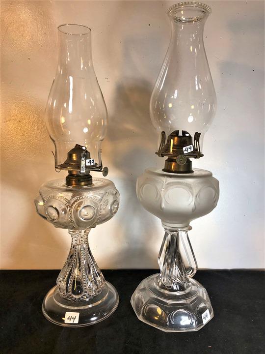 Pair of Decorative clear 19th Century Oil Lamps to: This pair of decortative 19th century oil lamps includes a Miller Co oil lamp with a satin glass fount, and an oil lamp with with thumb print medallions and beaded details. They measure 19" tall X 6"