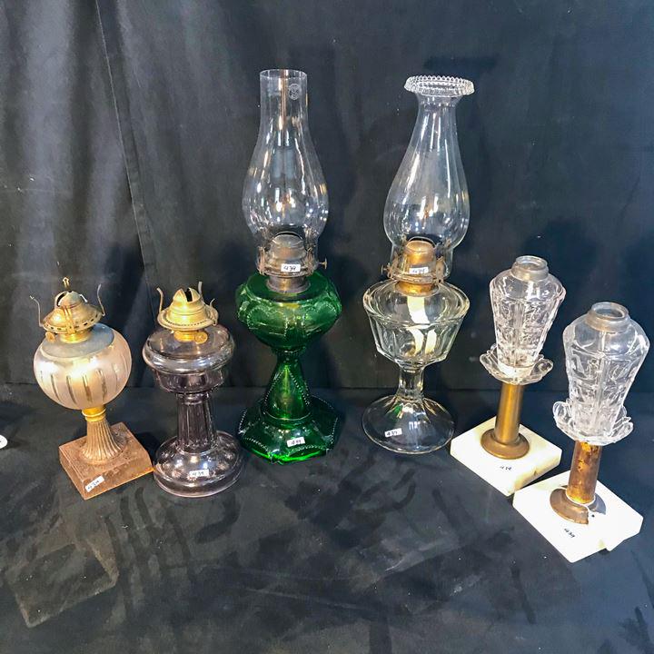 6 Early Oil lamps to include whale oil Lamps, Flint: This group of 6 early oil lamps include a green glass sweetheart lamp, an amethyst flint glass lamp, a striped frosted fount lamp with an iron base, a large clear pressed glass lamp, and a pair of ear
