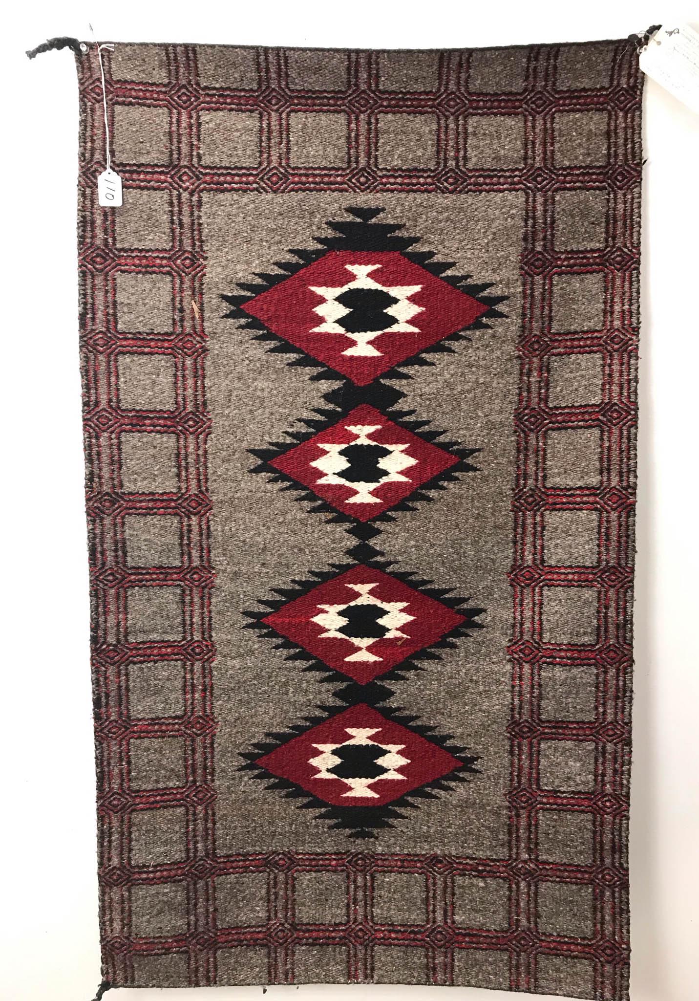 1900's Navajo Ganado Rug By Martha Trooie: This 1900's hand woven wool Navajo Ganado rug is by weaver Martha Trooie and carries a certificate of authenticity. It is in grey, white, red and black. In excellent condition, it measures 48" long X