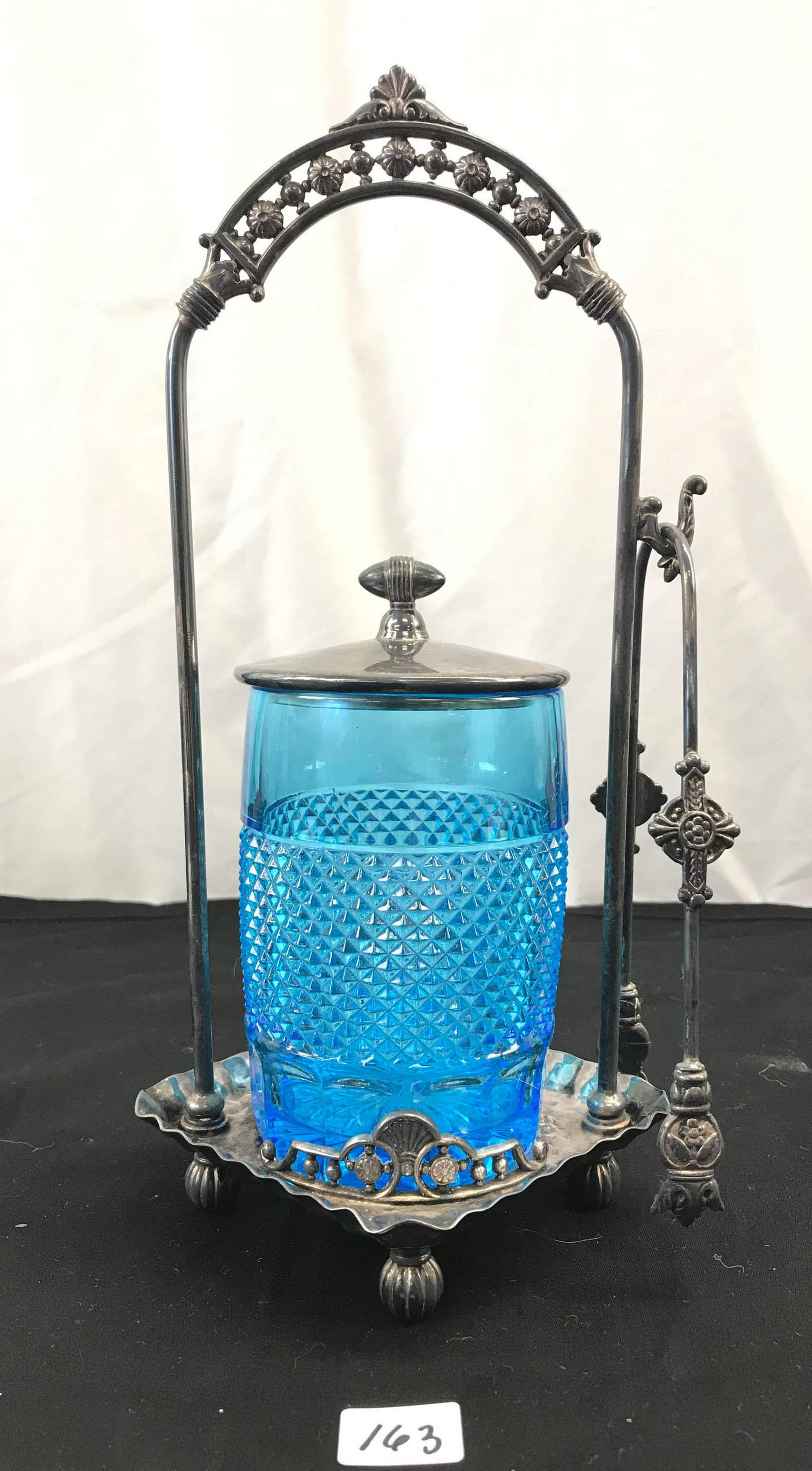 1800's Tufts Pickle Canister: This 1800's Tufts pickle canister has ornate carrier along with its original tongs. It measures 11" tall X 6" across.