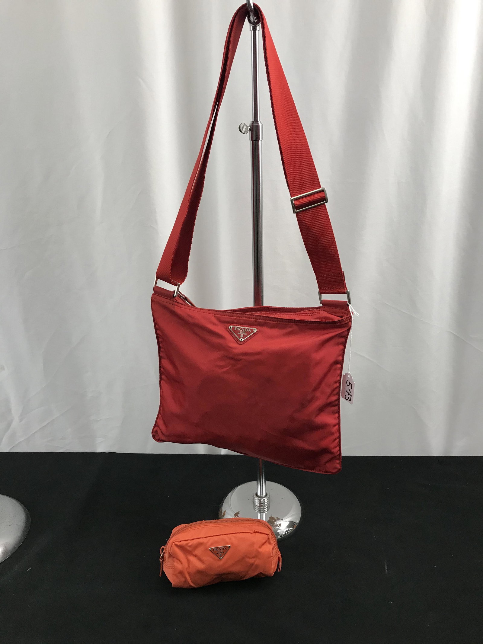Red Prada Tessuto Shoulder Bag, More!: This Red Prada shoulder bg has an adjustable strap and a zip top. It measures 10" tall X 11" across). 2 black marks on reverse side. Also included is an orange Prada tessuto zippered pouch in good con