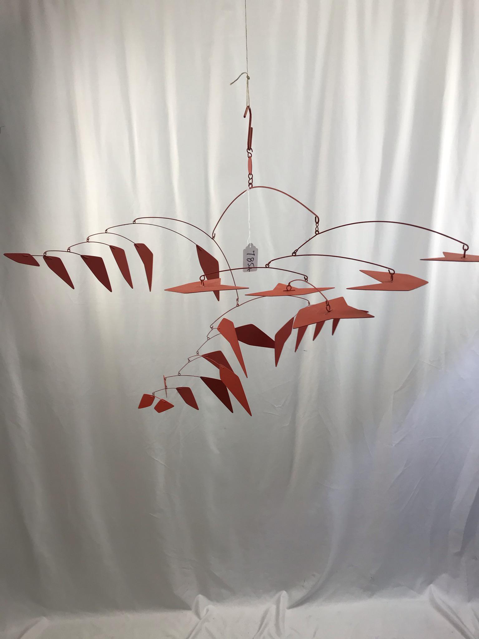 Arthur Bauman MCM Kinetic Hanging Mobile: This 1970's Arthur Bauman red metal kinetic mobile is in the style of Alexander Calder with multiple arms and metal shapes is initialed on the disc. It measures 24" tall X 39" across.