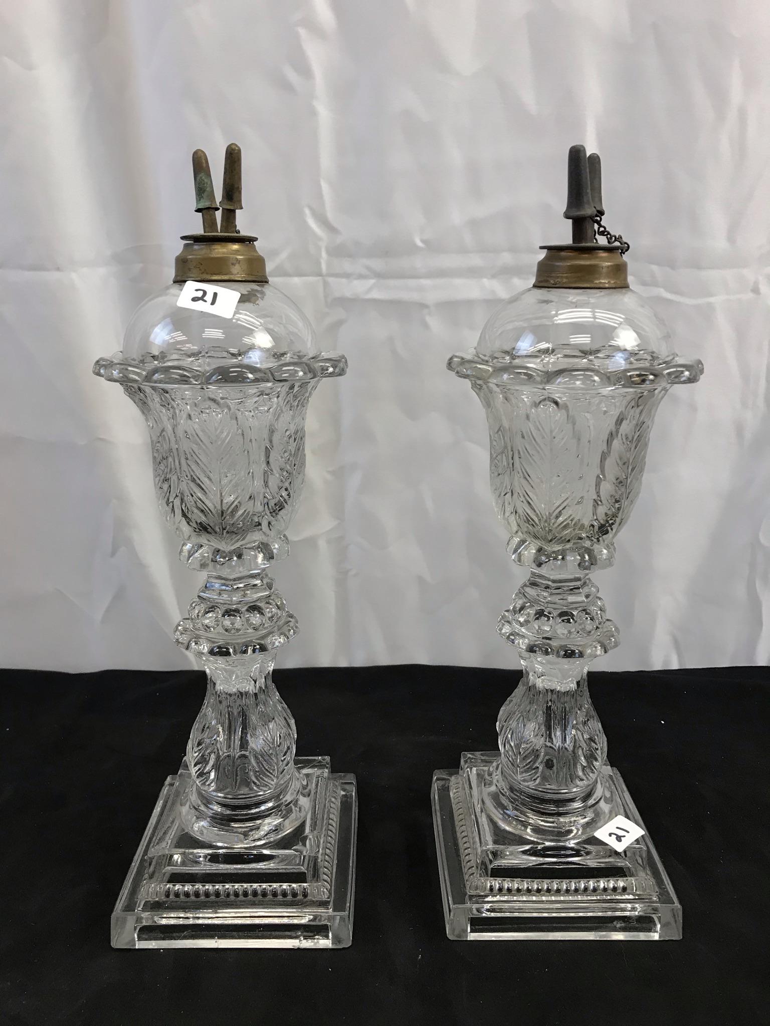 Pair of Sandwich Glass Philadelphia Whale Oil Lamps: A 1800's matching pair of Sandwich glass whale oil lamps in an acanthus leaf pattern of important size. Each lamp measures 14" tall X 4.5" across and retain their original burners, and burner caps.