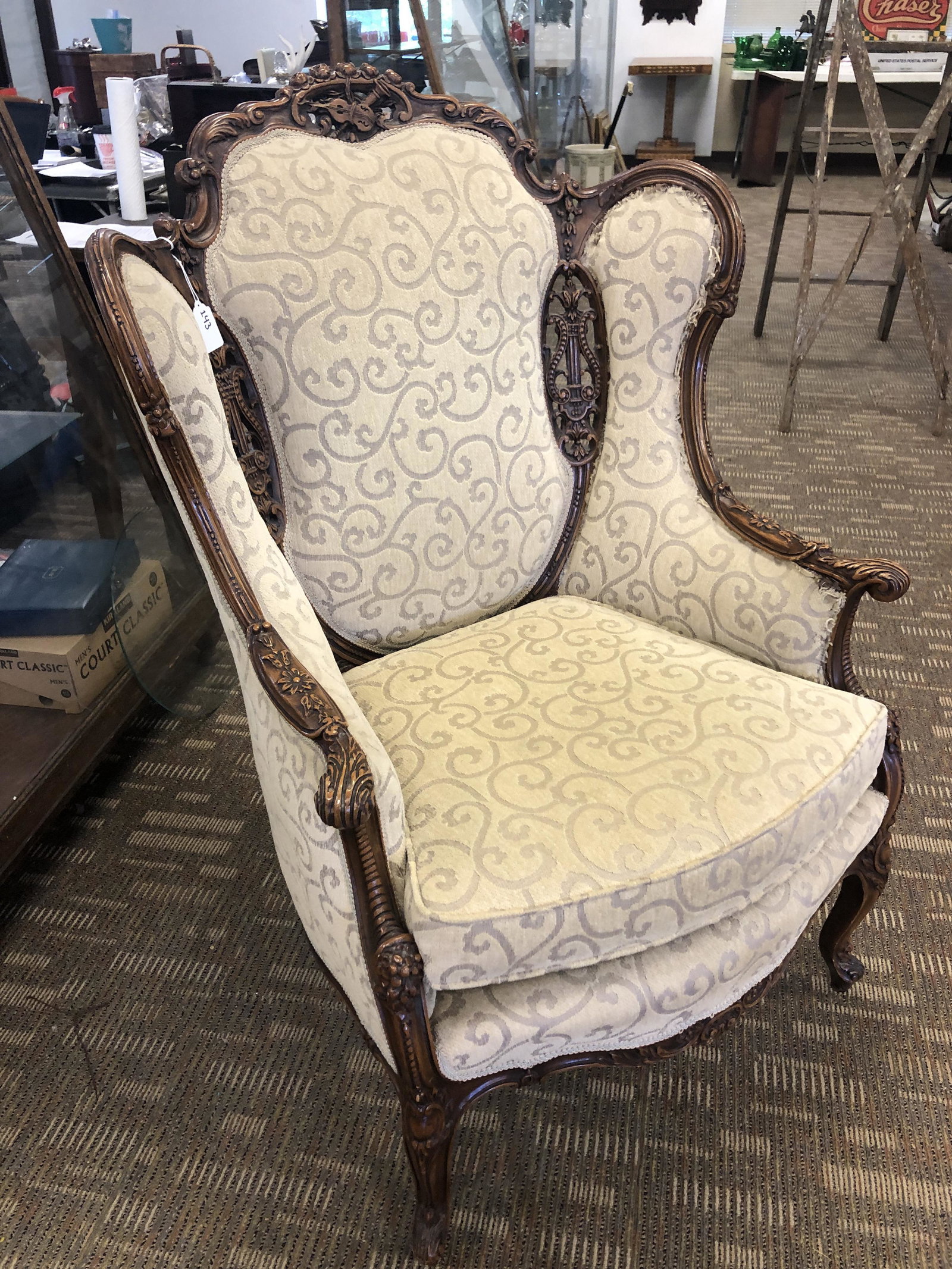 Carved French Winged Armchair: A 1920s pierced carved French winged armchair. Piercings depict various musical instruments. Newly upholstered with garland decorations in good condition, one section of edge trim on upholstery needs 