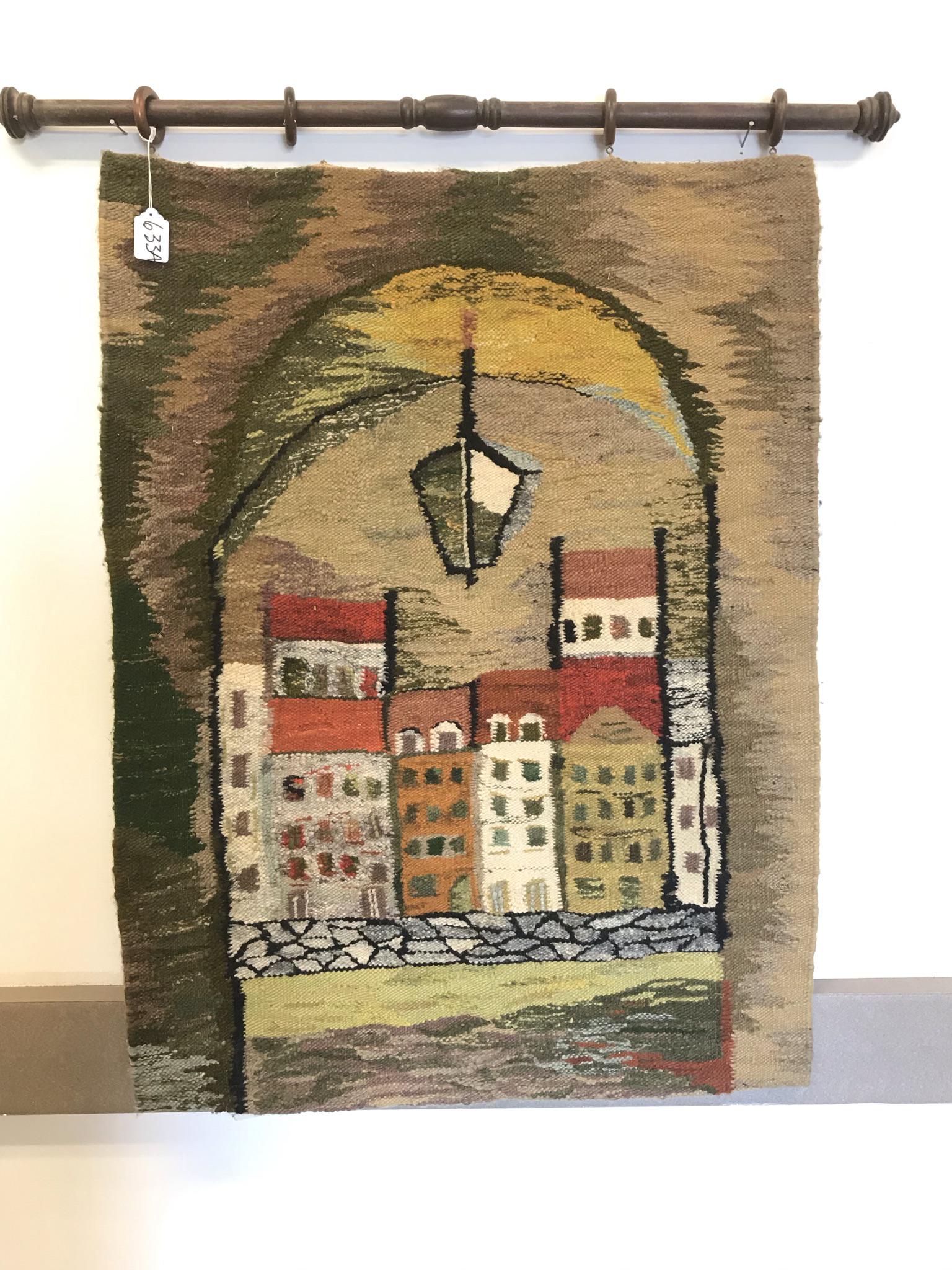 Mid Century Wool Weaving: This 1960's Mid-Century wool wall-hung weaving was made in Poland and depicts a group of houses seen through an archway. It hangs from a wooden rod and measures 43" tall X 38" across.