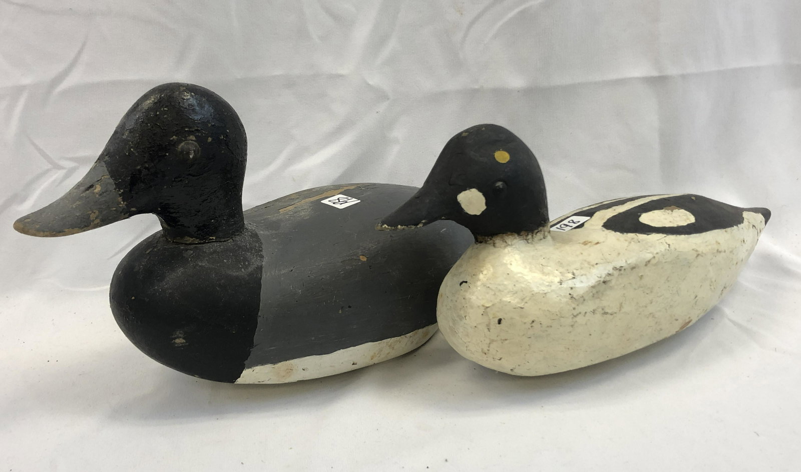 Lot of 2 Antique Duck Decoys: A lot of 2 wooden duck decoys with tack eyes. One duck has splits noted and is missing bottom weight, ducks appear to have been repainted at some point. One decoy is a blue bill and has the makers nam