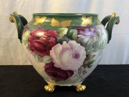 Handpainted Limoge Footed Jardinaire: An exquisitely hand painted floral and gold leaf footed jardinaire of imortant size. Planter has two handles and is marked "D & C France" on bottom. This piece measures 10" tall X 15" across.