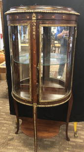 Petite Demilune Display Case: A light up demilune handpainted display cabinet with serpentine legs. This piece measures 55.5" tall X 26" across X 14" deep.