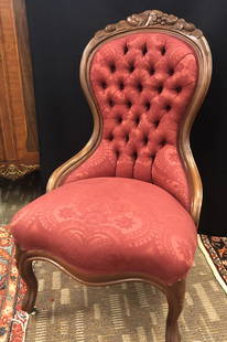 Victorian Button Tufted Parlor Chair: A Victorian button tufted burgundy brocade upholstered parlor chair in walnut with fruit carvings on crest. This chair measures 40" tall X 18" deep X 23" across.