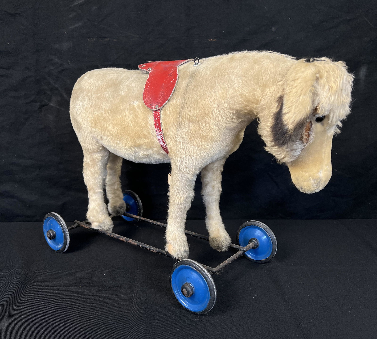 1900's Rideable Horse Squeaker: This 1900's rideable squeaker horse (squeaker works) is in fair condition, is straw stuffed on wheels with glass eyes and original saddle. Has a tag that says made in the US Zone. It measures 21" long