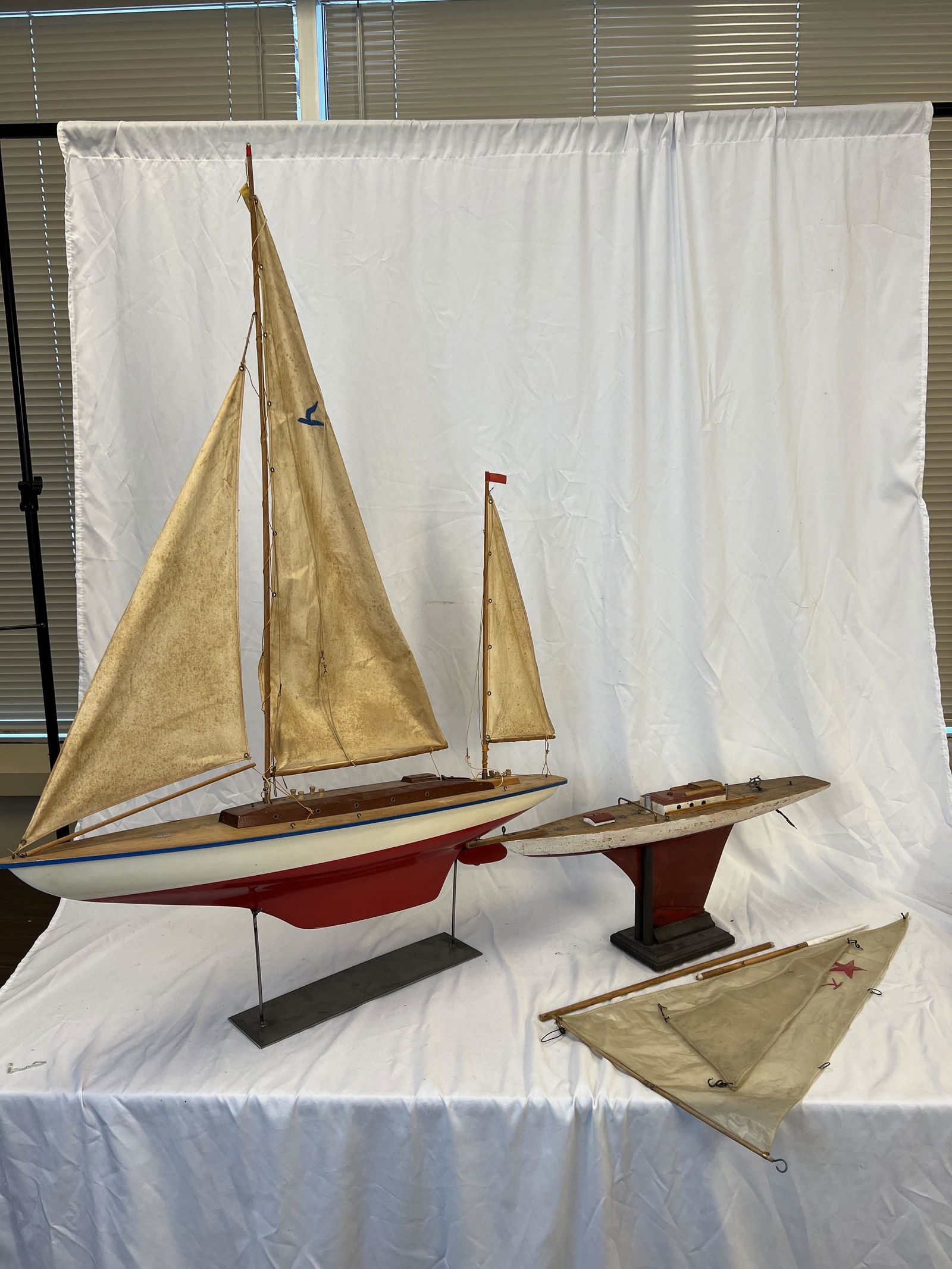 2 Wooden Sailboats on Stands c. 1940's: 2 1940s wooden sailboats on stands with elaborate rigging and sails. They retain their original paint and most likely would sail in a pond. The larger boat measures 37" long and the smaller boat measu