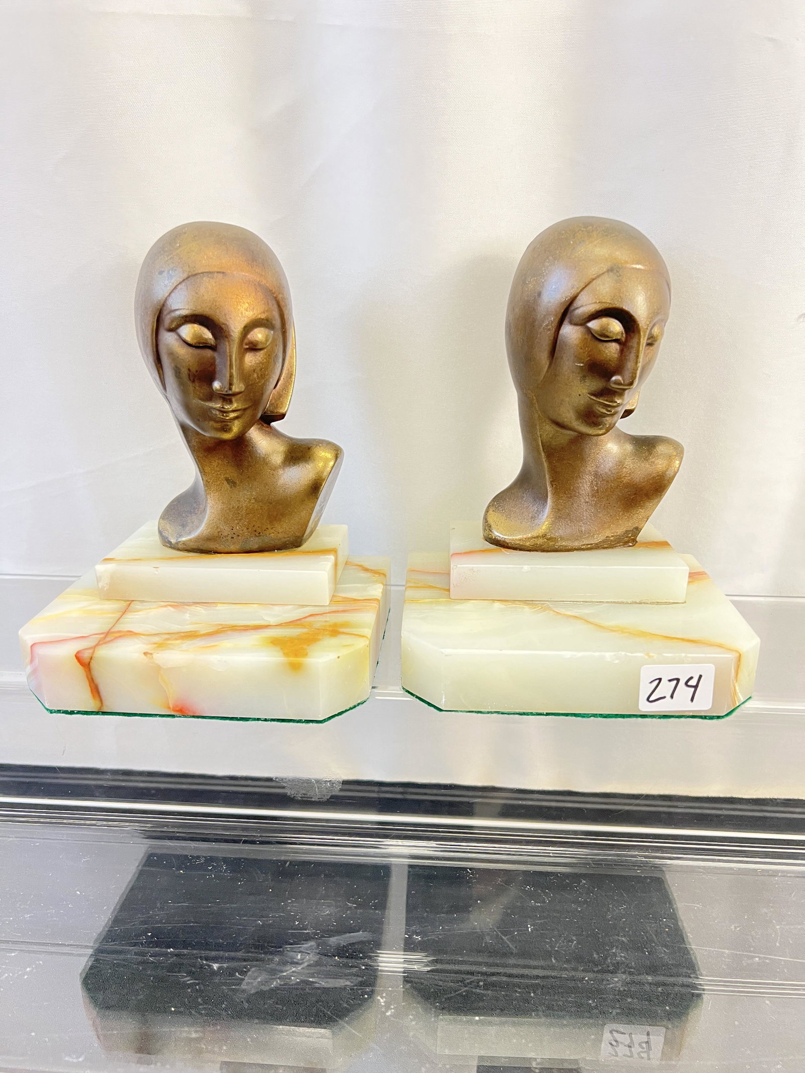 Art Deco 1920's Book Ends: This pair of 1920's patinated bronze Art Deco bookends have stylized women's heads on stepped marble bases. They each measure 6" tall X 4.5" across X 4" deep.