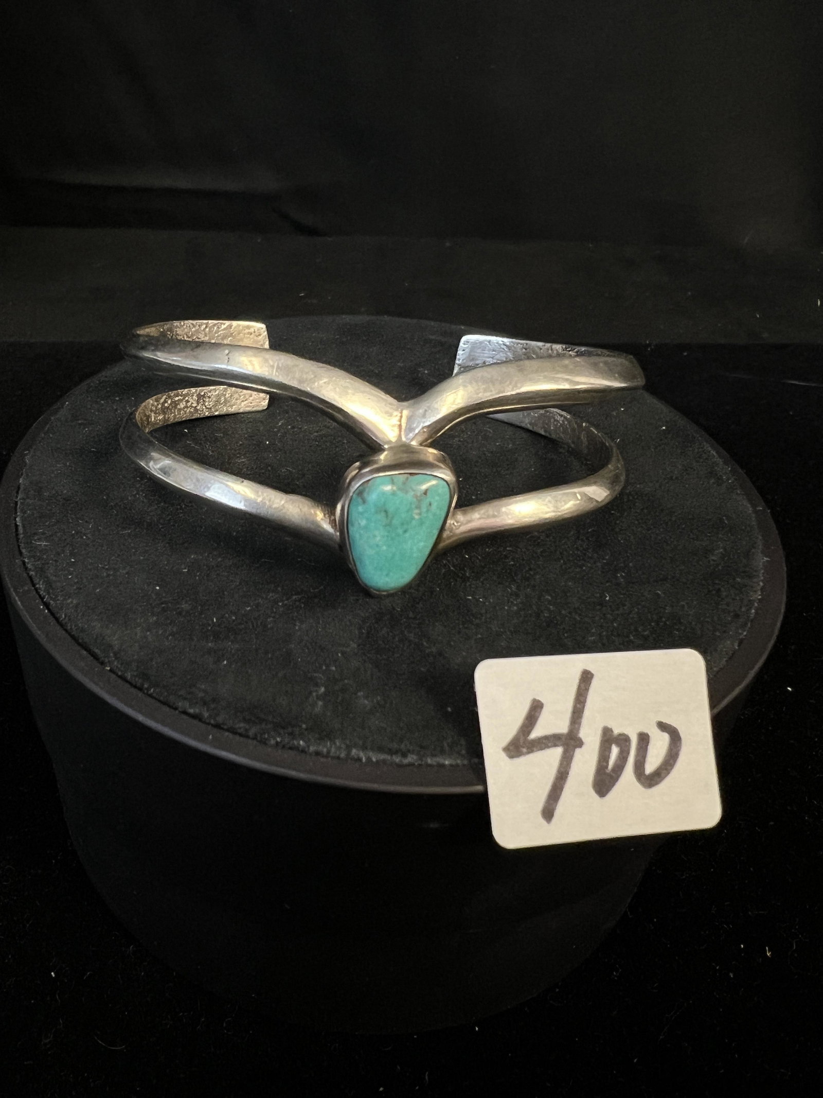 Sterling and Turquoise Cuff Bracelet: A sterling and turquoise Navajo cuff bracelet. Inside is marked "C Sterling" and features a turquoise set in center at point. Bracelet measures 1" tall X 6" around.
