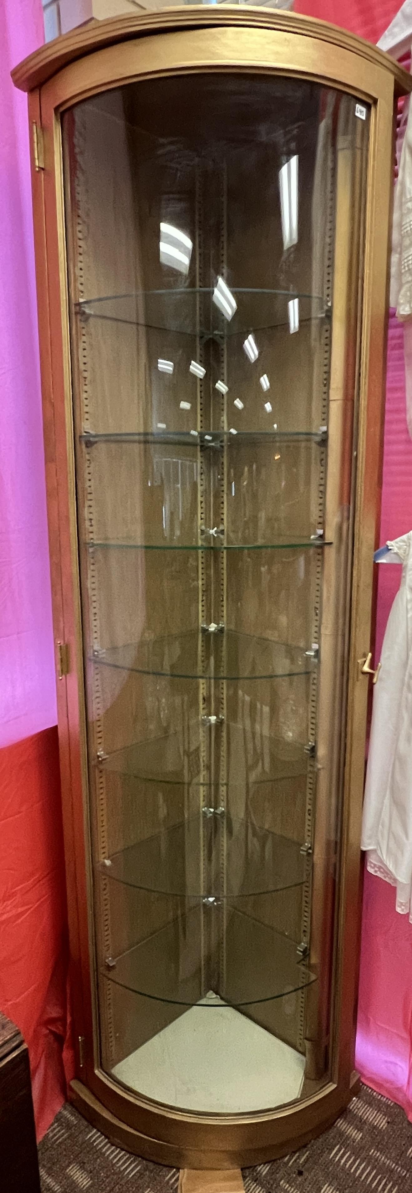 Single-Door Curved Glass Corner Display Cabinet: A single-door curved glass display corner china cabinet with seven shelves that lights up. It measures 7' tall.