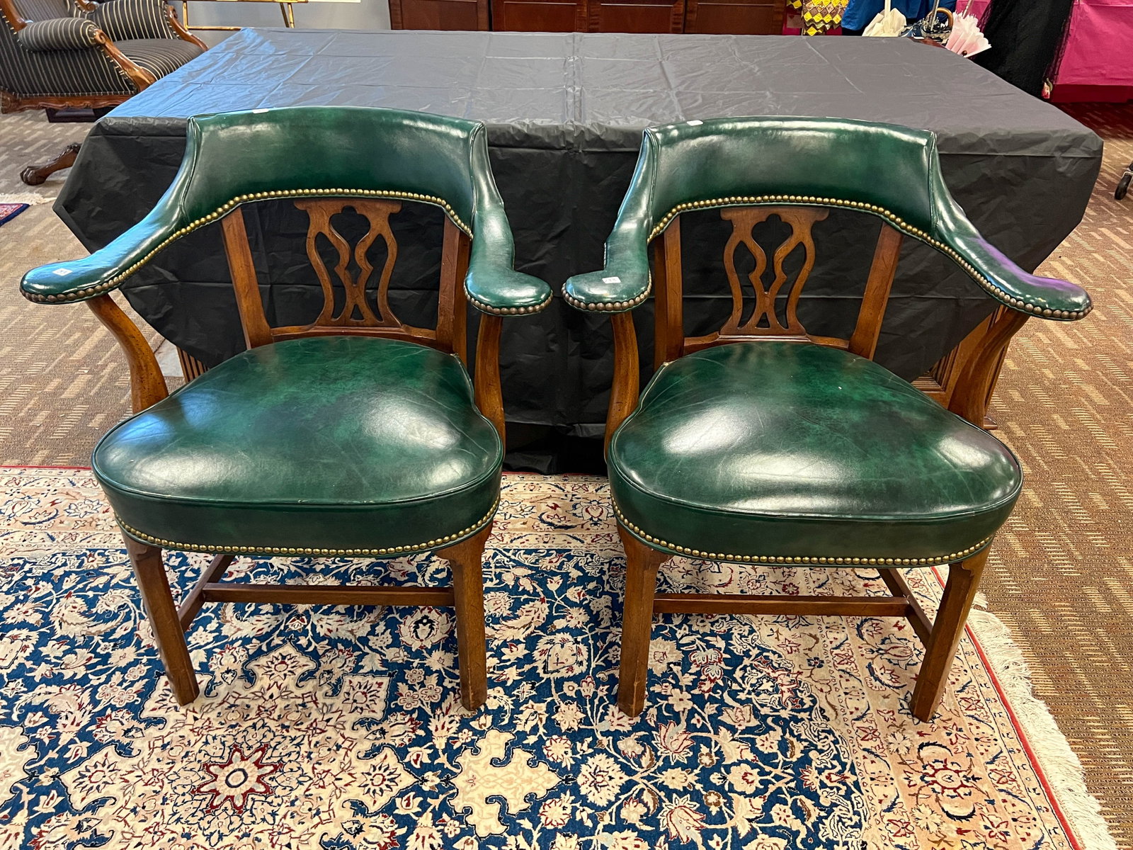 A pair of Chippendale office armchairs: A pair of Chippendale office armchair in mahogany and green leather with brass tack trim. They measure 31 in tall by 28 in across by 21 deep.