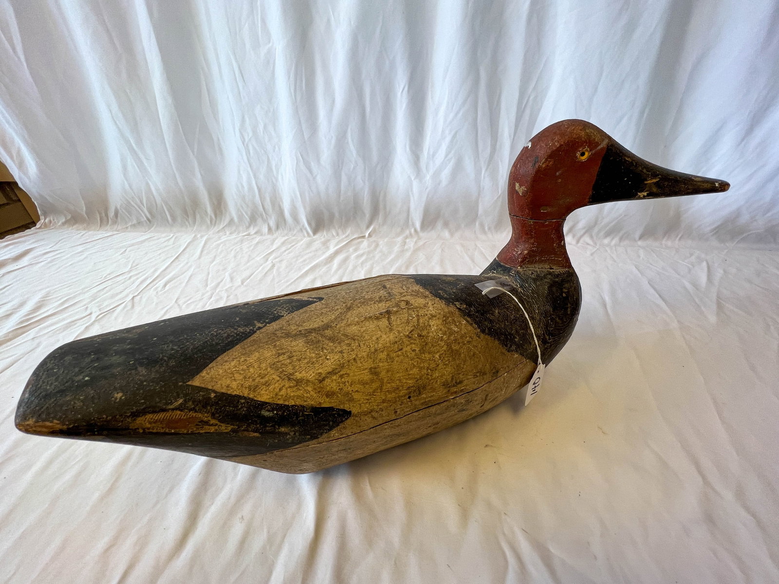 Hand carved Wisconsin antique duck decoy (possibly Moak): A hand carved Wisconsin duck decoy in its original paint with glass eye. It has a separation crack on ducks body noted and shrinkage to head from body noted. It measures 10 in tall by 17 in long by 5 