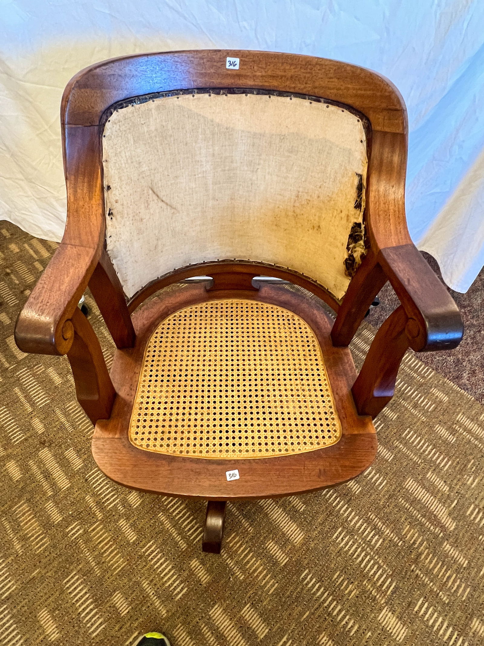 1900s Mahogany Armed Swivel Roll Top Desk Chair: 1900s Mahogany armed swivel roll top desk chair with cane seat and upholstered back. This needs to be reupholstered on back and front, otherwise refinished condition. Measures 34" tall by 24" across b
