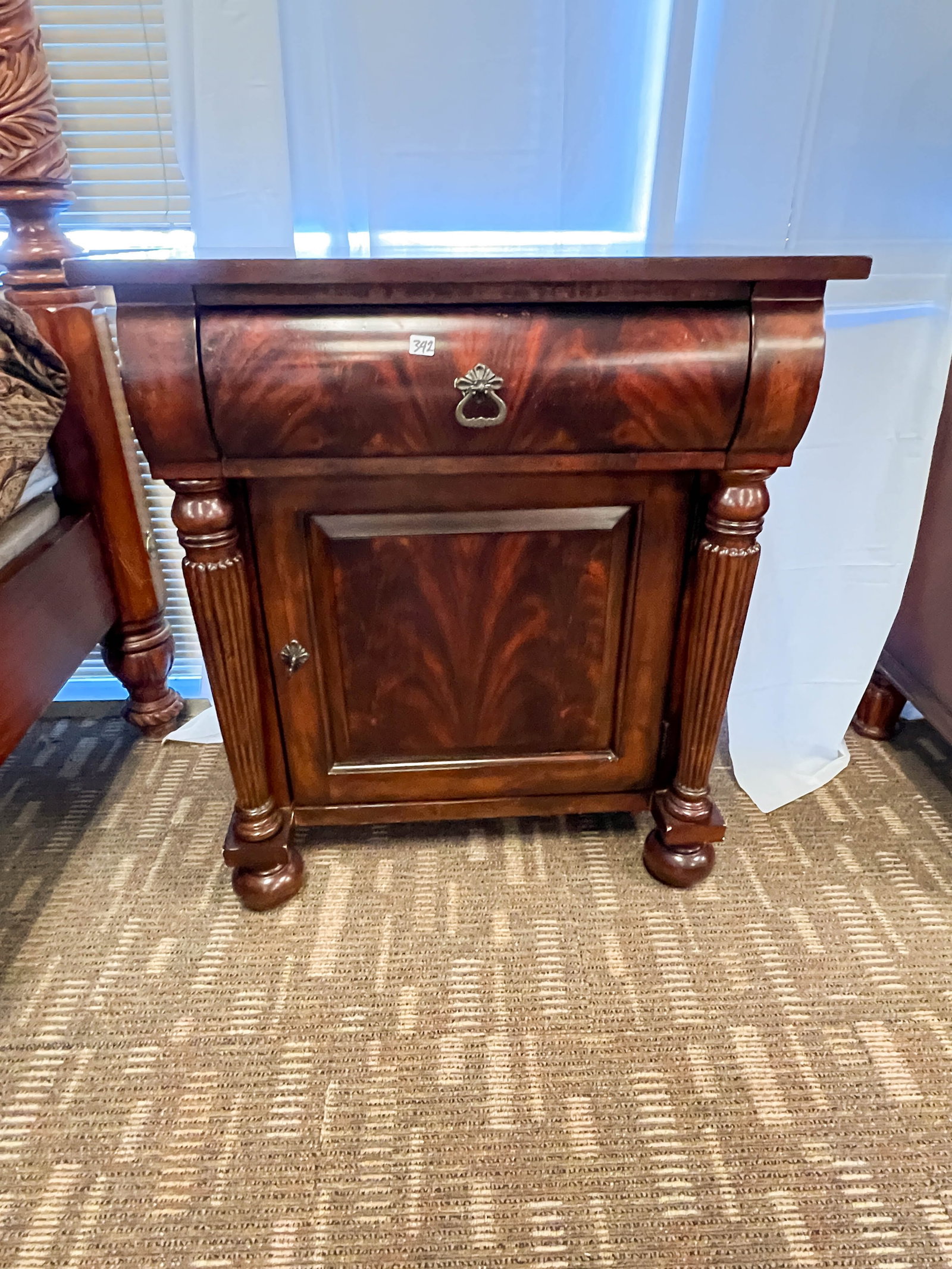 Pair of Flamed Mahogany Single Drawer Nightstands with Cabinet Base, Pillared Front: Pair of flamed mahogany single drawer nightstands with cabinet base, pillared front, and chamfered panels. There is a label inside that reads "Design in America by The National Trust, Crafted by Hamma