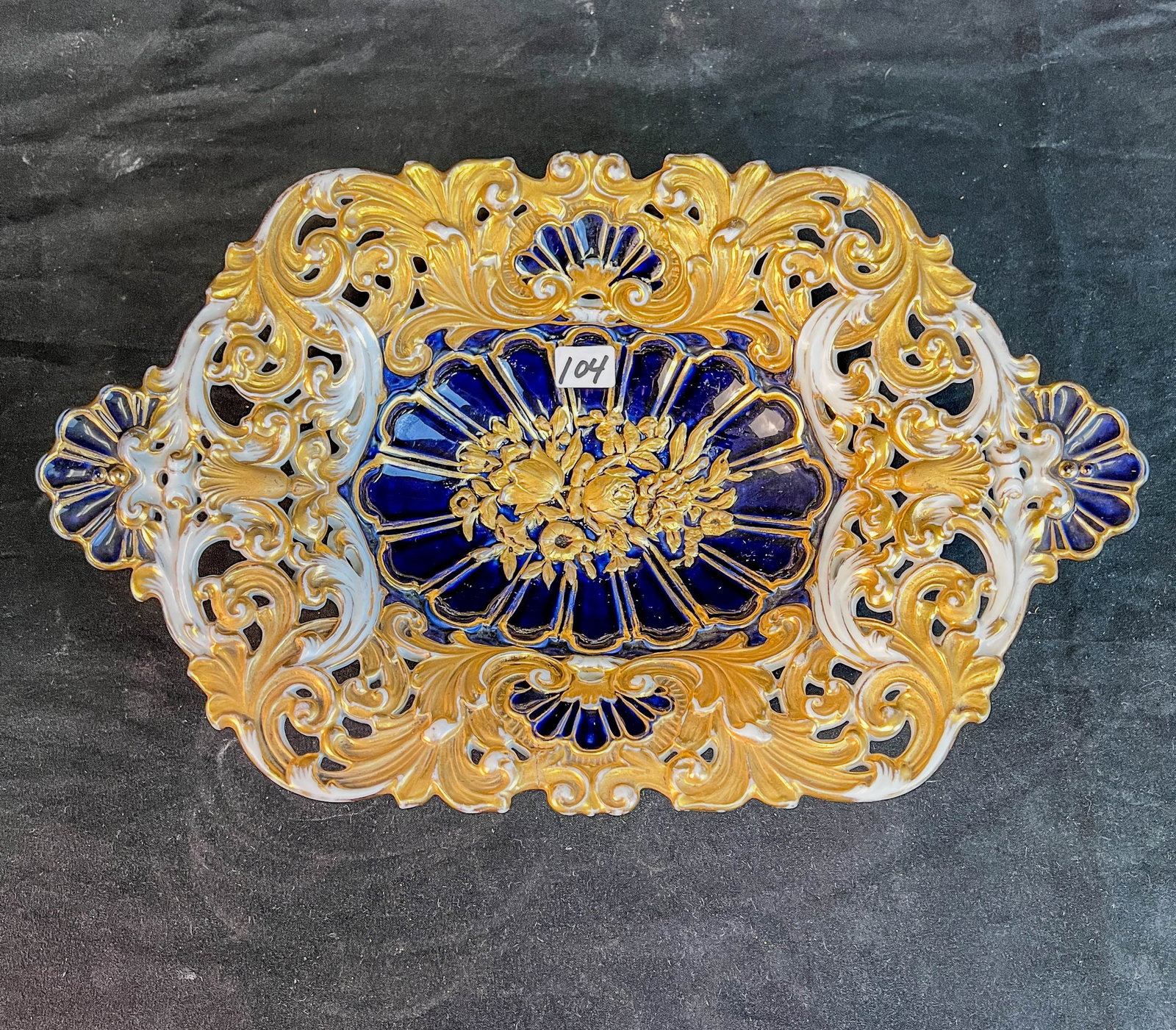 Meissen Reticulated and Gilded Porcelain Bowl C. 1830/40"s: This Meissen porcelain cobalt and heavy gold reticulated bowl c.1830/40's has two scalloped side handles and rose decoration in its center. It has the Ross sword hallmark on its bottom. Minor firing c